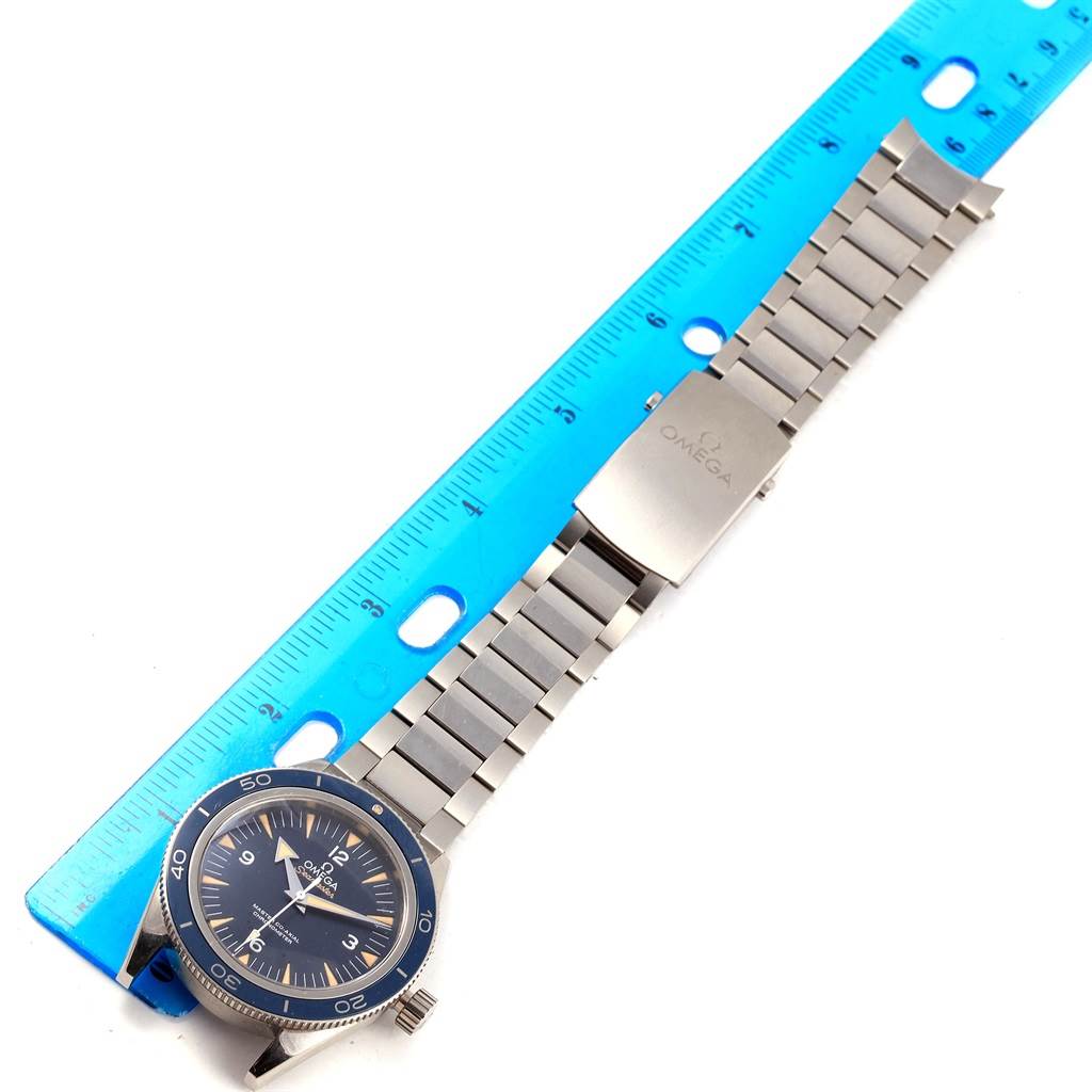 The image shows an Omega Seamaster 233.90.41.21.03.001 Men's Titanium Blue Dial 233.90.41.21.03.001 Men's Titanium Blue Dial watch face and its metal bracelet laid next to a blue ruler.