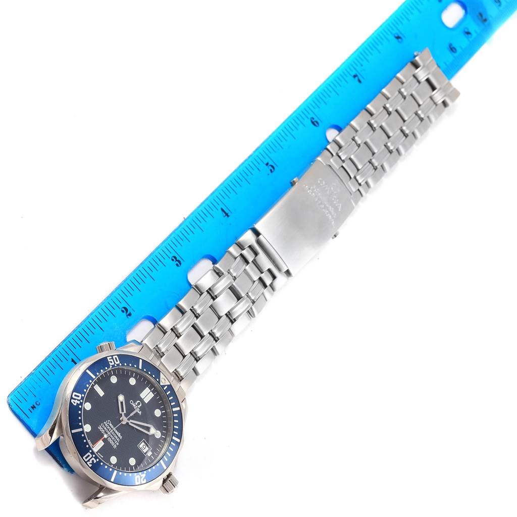 The image shows an overhead view of an Omega Seamaster 2531.80.00 Men
s Stainless Steel Blue Dial 2531.80.00 Men
s Stainless Steel Blue Dial watch with its metal bracelet stretched out alongside a blue ruler.