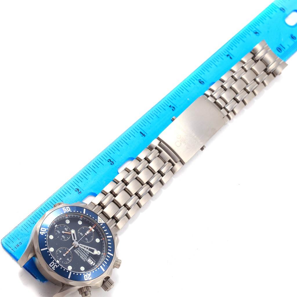 The image shows an Omega Seamaster 2298.80.00 Men
s Titanium Blue Dial 2298.80.00 Men
s Titanium Blue Dial watch laid flat with its bracelet and clasp next to a blue ruler, viewed from the top.