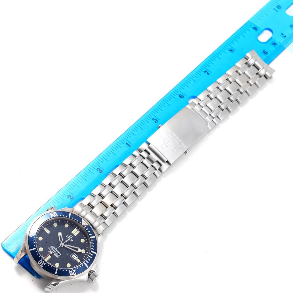 The image shows an Omega Seamaster 2541.80.00 Men
s Stainless Steel Blue Dial 2541.80.00 Men
s Stainless Steel Blue Dial watch positioned next to a blue ruler, highlighting its face, bezel, and stainless steel bracelet.