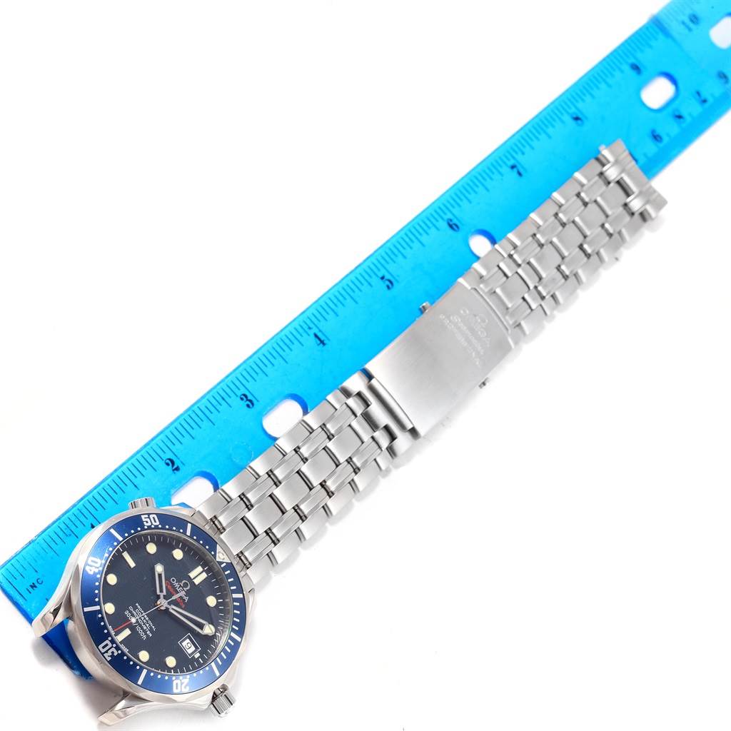 The Omega Seamaster 2220.80.00 Men
s Stainless Steel Blue Dial 2220.80.00 Men
s Stainless Steel Blue Dial watch is shown from a top-down angle, displaying its face, bezel, and metal bracelet alongside a ruler.