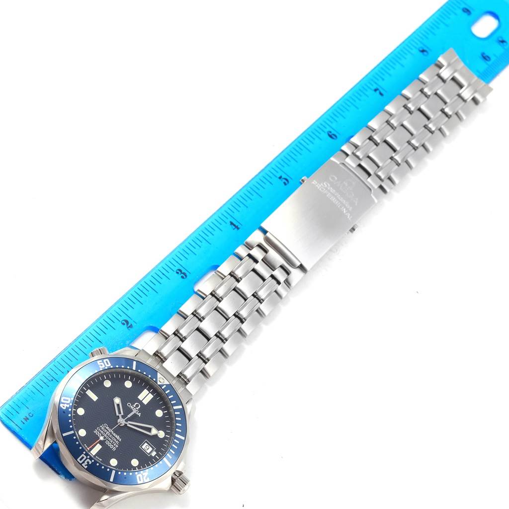 The Omega Seamaster 2531.80.00 Men's Stainless Steel Blue Dial 2531.80.00 Men's Stainless Steel Blue Dial watch is shown from an overhead angle, including its face, bracelet, and clasp, next to a blue ruler.