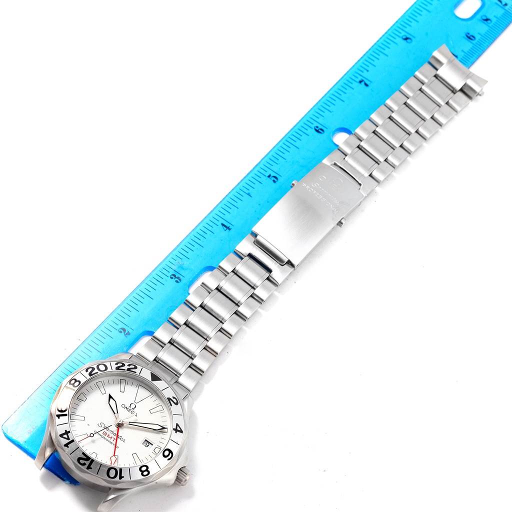 The Omega Seamaster 2538.20.00 Men
s Stainless Steel White Dial 2538.20.00 Men
s Stainless Steel White Dial watch is shown from an overhead angle, highlighting the face, bezel, and steel bracelet alongside a blue ruler.