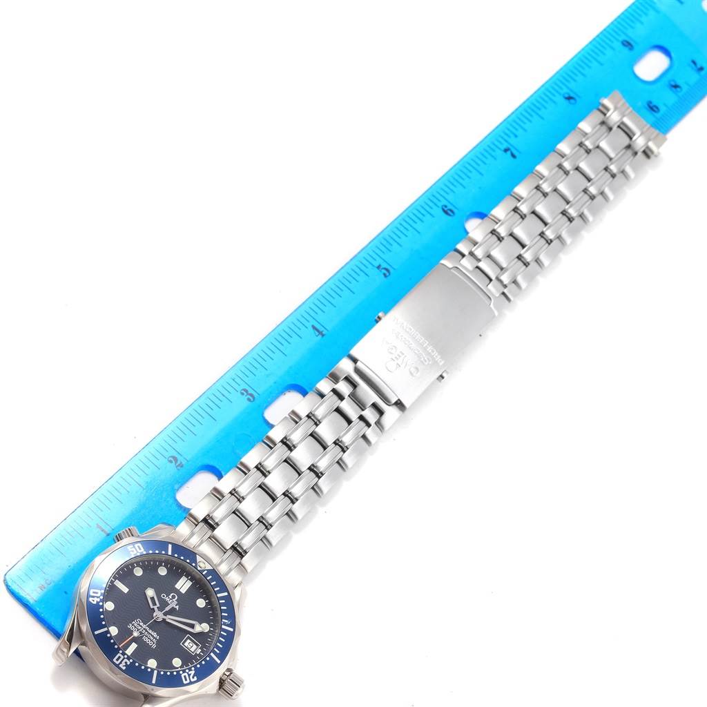 This image shows an Omega Seamaster 2561.80.00 Men
s Stainless Steel Blue Dial 2561.80.00 Men
s Stainless Steel Blue Dial watch laid flat with a blue measuring ruler to its left, displaying the face and steel bracelet.