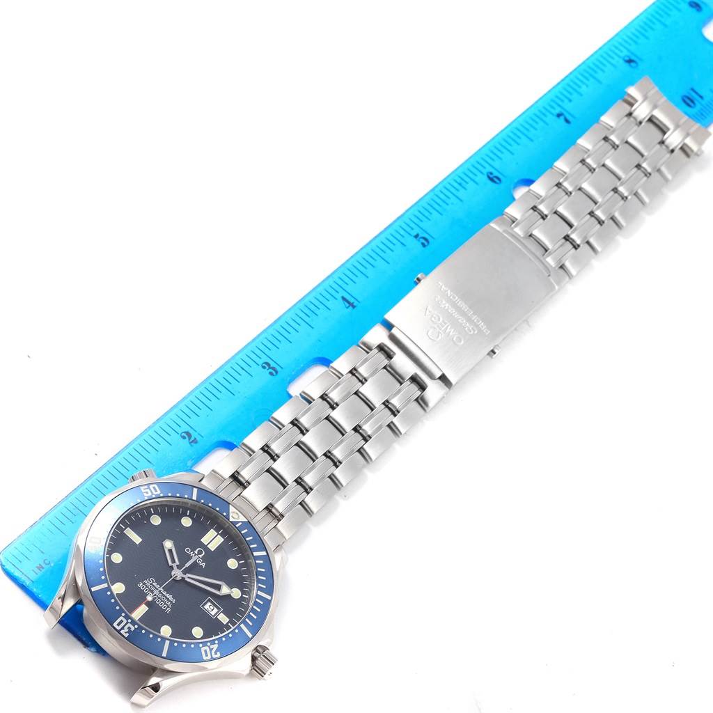 This image shows an overhead view of an Omega Seamaster 2541.80.00 Men
s Stainless Steel Blue Dial 2541.80.00 Men
s Stainless Steel Blue Dial watch, displaying the face and stainless steel bracelet next to a blue ruler.