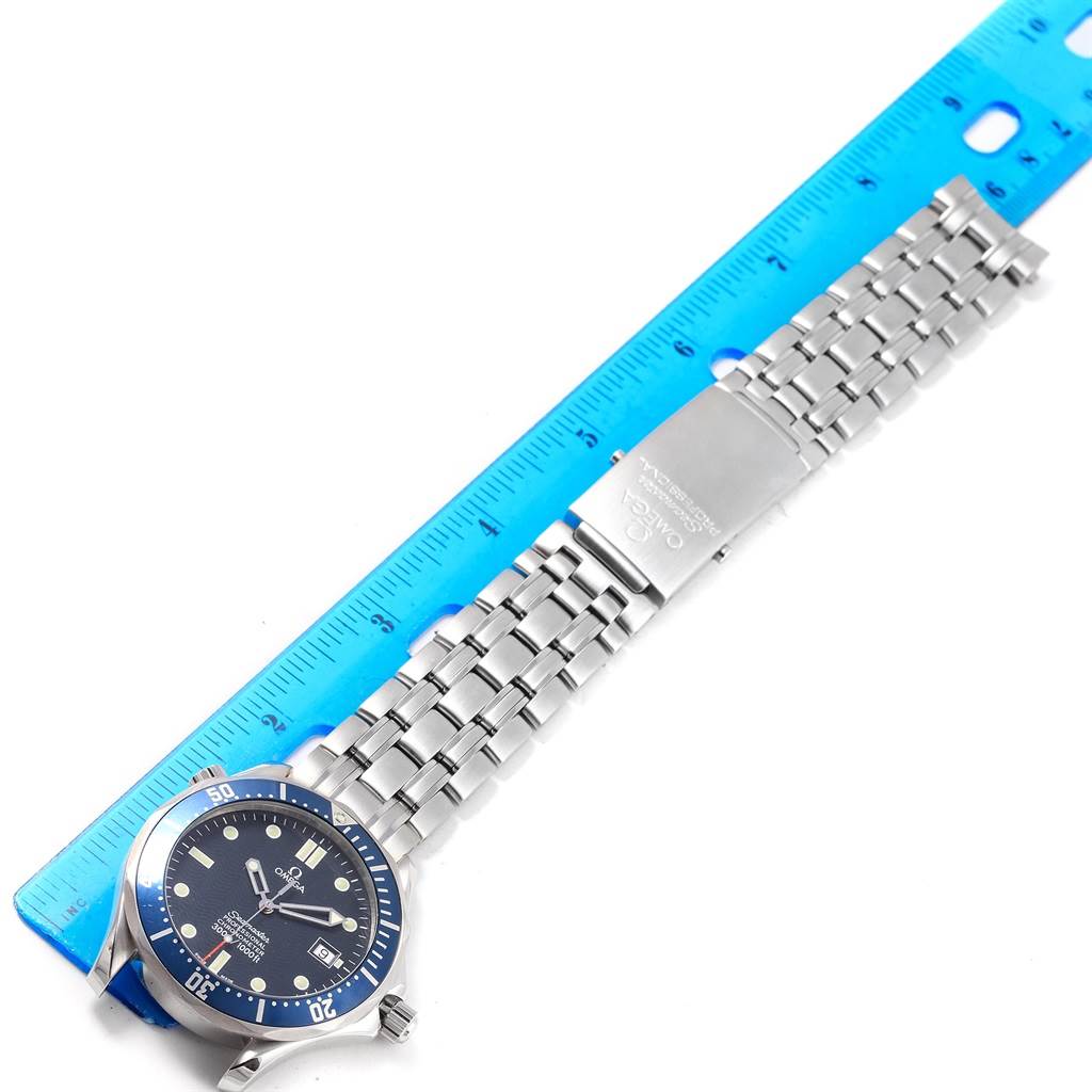 The Omega Seamaster 2531.80.00 Men
s Stainless Steel Blue Dial 2531.80.00 Men
s Stainless Steel Blue Dial watch is pictured horizontally, showcasing its face, bezel, and metal bracelet beside a blue ruler.