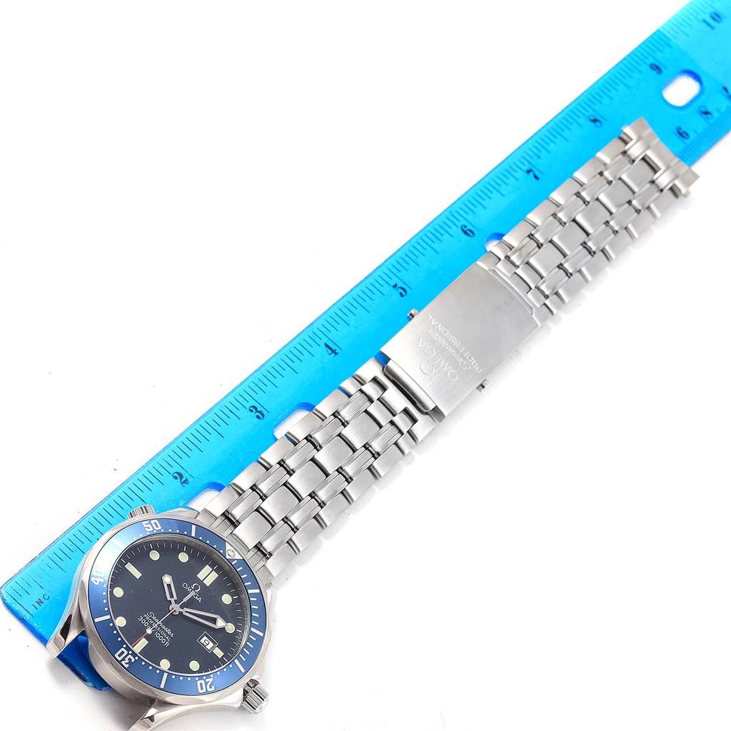 The Omega Seamaster 2541.80.00 Men
s Stainless Steel Blue Dial 2541.80.00 Men
s Stainless Steel Blue Dial watch is shown in a top-down angle, displaying the face, bracelet, and clasp next to a blue ruler.