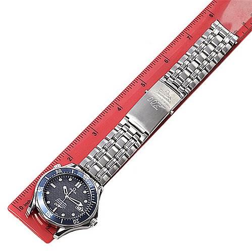 The image shows an Omega Seamaster Men's Stainless Steel Blue Dial Men's Stainless Steel Blue Dial watch laid flat next to a red ruler, displaying its dial, bezel, and metal bracelet.