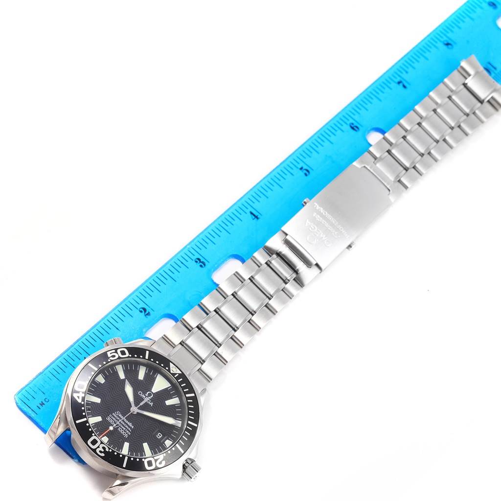 The Omega Seamaster 2254.50.00 Men
s Stainless Steel Black Dial 2254.50.00 Men
s Stainless Steel Black Dial watch is shown from a top-down angle, displaying its face, bezel, and stainless steel bracelet alongside a blue ruler.