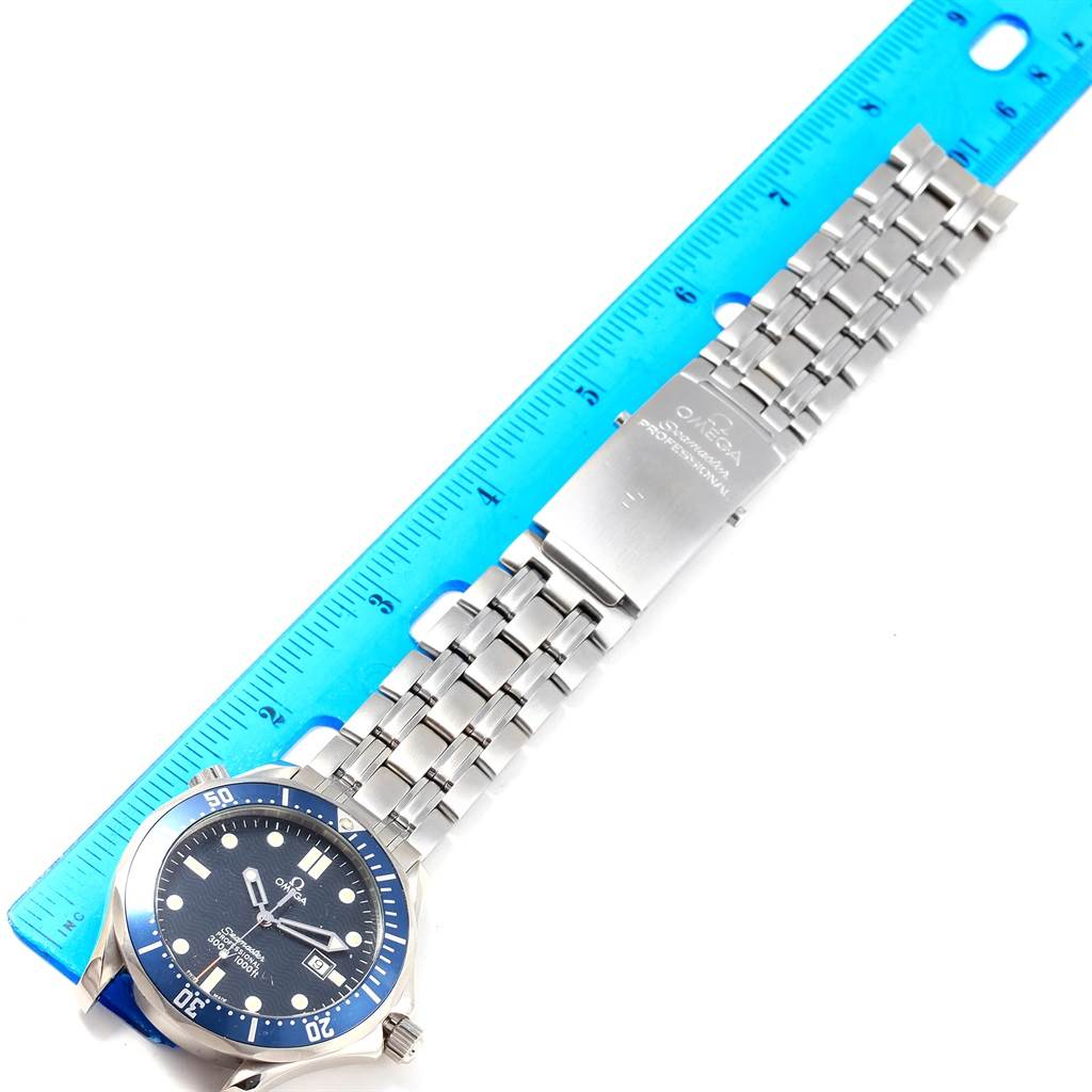 The Omega Seamaster 2541.80.00 Men
s Stainless Steel Blue Dial 2541.80.00 Men
s Stainless Steel Blue Dial watch is shown from a top-down angle, displaying the face, bezel, and metal bracelet alongside a blue ruler.