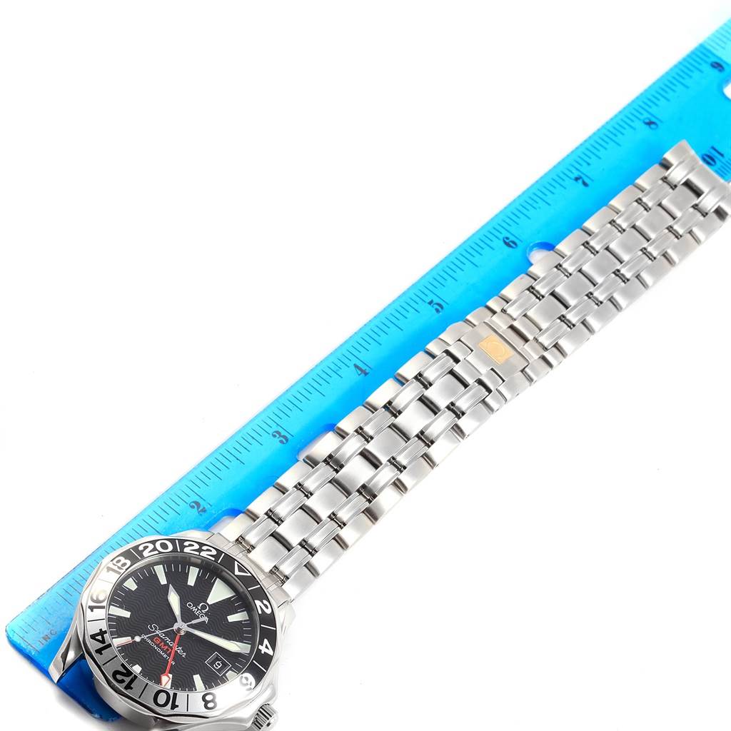 The image shows an Omega Seamaster 2536.50.00 Men
s Stainless Steel Black Dial 2536.50.00 Men
s Stainless Steel Black Dial watch with a silver bracelet next to a ruler, angled flat from the side.