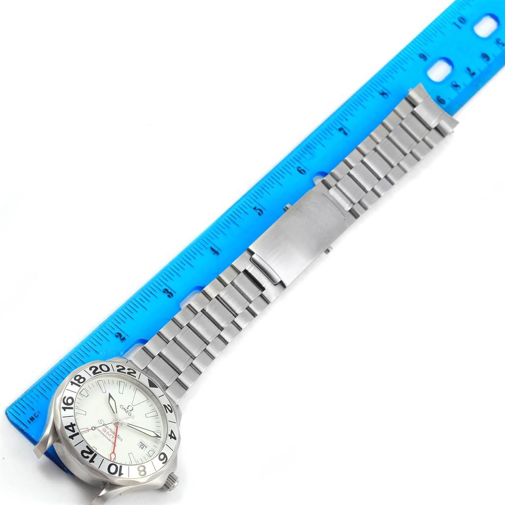 This Seamaster model by Omega is shown from a top-down angle, displaying the watch face, bezel, bracelet, and clasp next to a blue ruler.