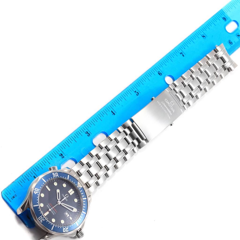 The image shows the front view of an Omega Seamaster 2221.80.00 Men
s Stainless Steel Blue Dial 2221.80.00 Men
s Stainless Steel Blue Dial watch with its silver bracelet measured against a blue ruler.