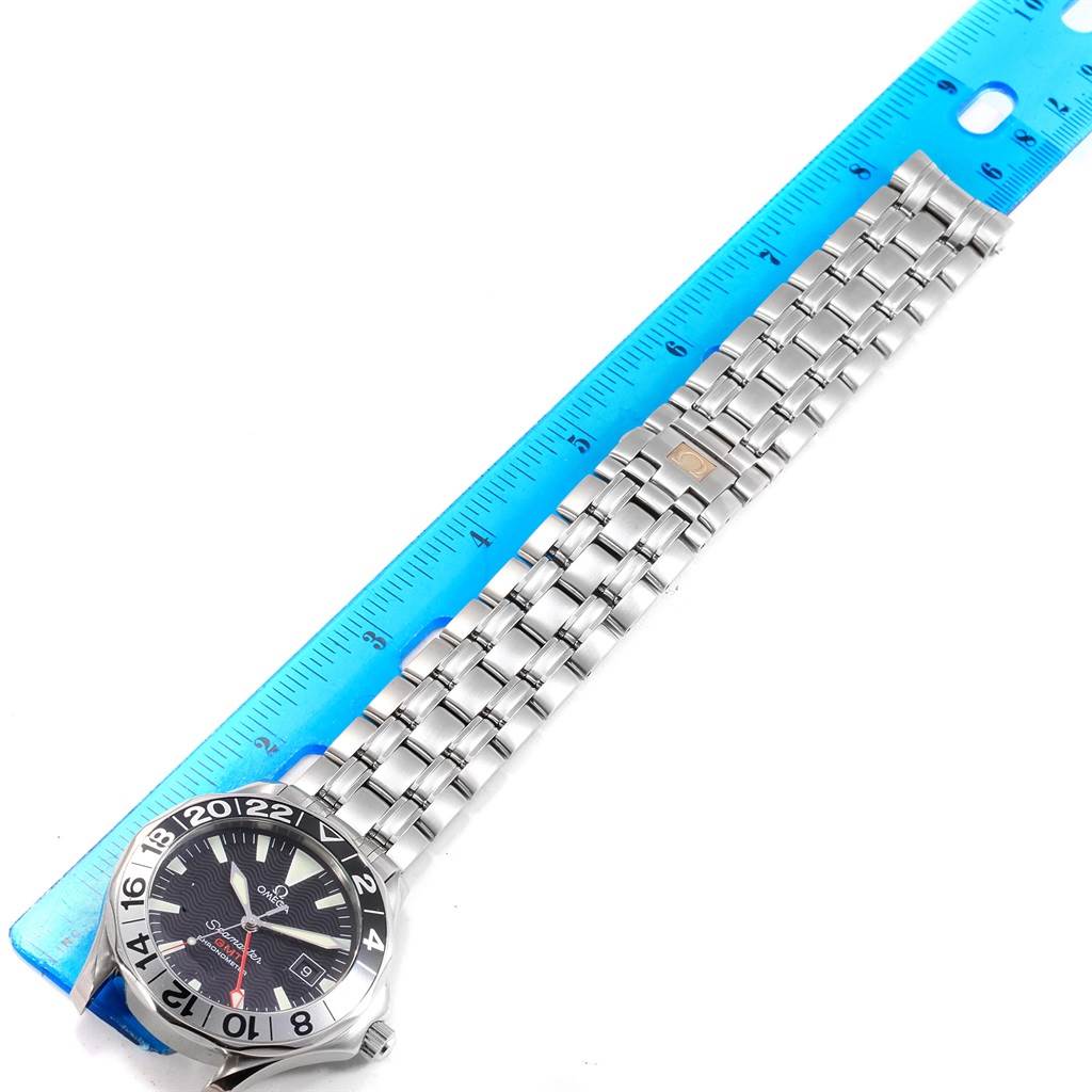 The image shows an Omega Seamaster 2534.50.00 Men
s Stainless Steel Black Dial 2534.50.00 Men
s Stainless Steel Black Dial watch laid flat beside a ruler, displaying its face and entire metal bracelet.