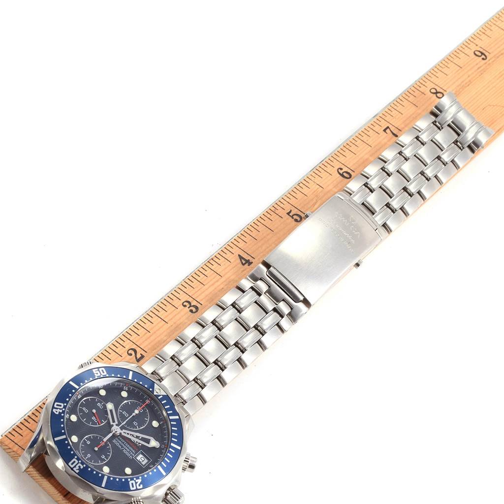 The image shows an Omega Seamaster 2225.80.00 Men
s Stainless Steel Blue Dial 2225.80.00 Men
s Stainless Steel Blue Dial watch laid flat, emphasizing its face, bracelet, and clasp with a wooden ruler for scale.