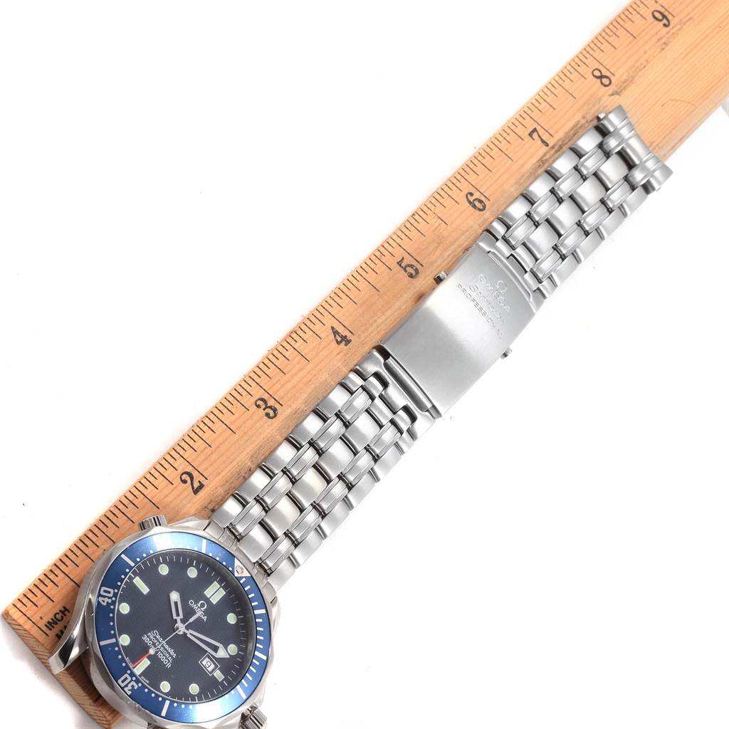 The image shows the Omega Seamaster 2541.80.00 Men
s Stainless Steel Blue Dial 2541.80.00 Men
s Stainless Steel Blue Dial watch laid flat against a wooden ruler, displaying the watch face and metal bracelet.