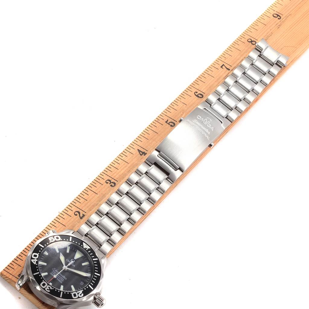 The image shows an Omega Seamaster 2252.50.00 Men
s Stainless Steel Black Dial 2252.50.00 Men
s Stainless Steel Black Dial watch laid flat, with part of the face and metal bracelet visible, measured next to a wooden ruler.