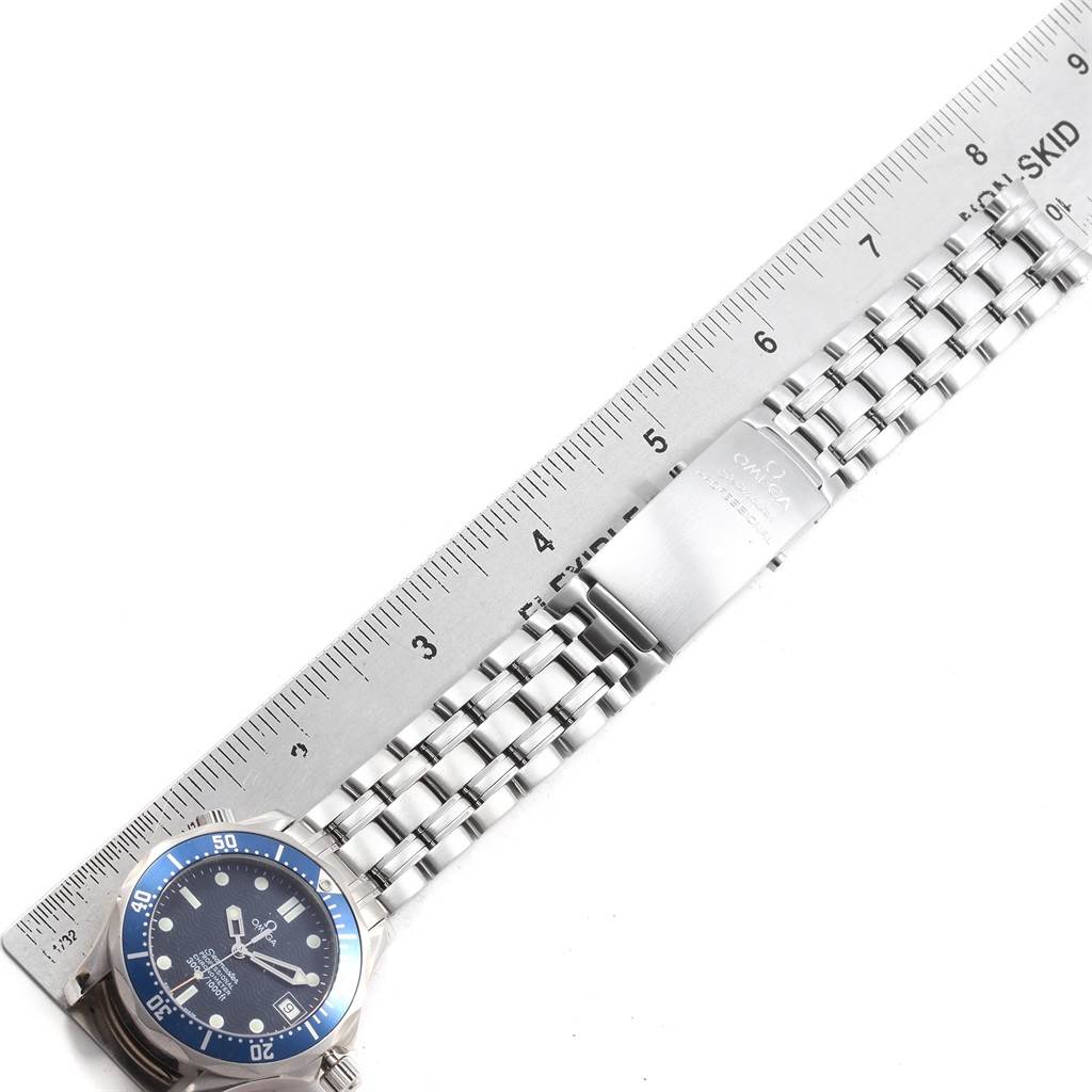 The image shows an Omega Seamaster 2551.80.00 Men
s Stainless Steel Blue Dial 2551.80.00 Men
s Stainless Steel Blue Dial watch lying flat with a ruler beside it, displaying the face, bezel, and metal bracelet.