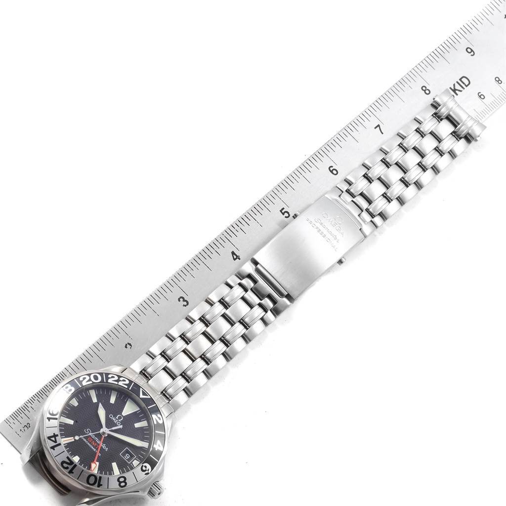 The Omega Seamaster 2234.50.00 Men
s Stainless Steel Black Dial 2234.50.00 Men
s Stainless Steel Black Dial watch is shown from a top-down angle, displaying the face, bracelet, and part of the clasp alongside a ruler for scale.