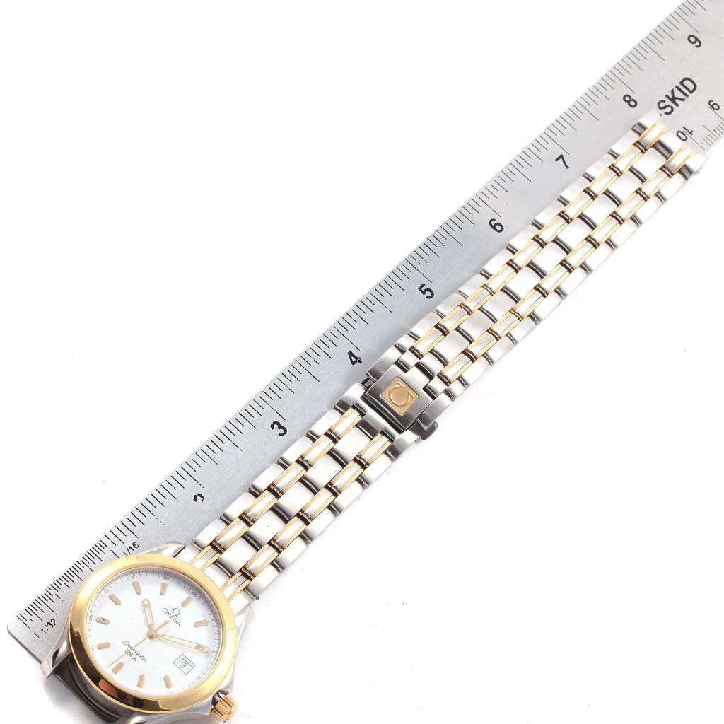 The image shows an Omega Seamaster 2311.21.00 Men's Steel and Gold (two tone) White Dial 2311.21.00 Men's Steel and Gold (two tone) White Dial watch angled diagonally, displaying the face, full bracelet, and partially clasped deployment buckle next to a ruler for scale.