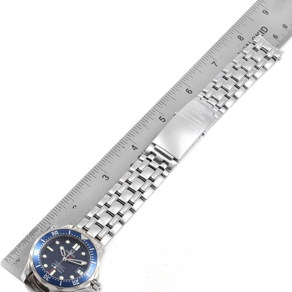 The Omega Seamaster 2222.80.00 Men
s Stainless Steel Blue Dial 2222.80.00 Men
s Stainless Steel Blue Dial watch is shown from a top-down angle, displaying its face, stainless steel bracelet, and deployment clasp next to a ruler.