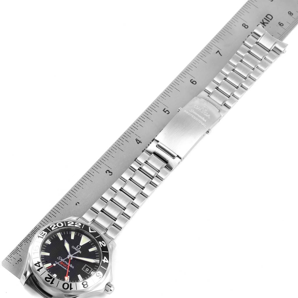 The image shows the Omega Seamaster 2234.50.00 Men
s Stainless Steel Black Dial 2234.50.00 Men
s Stainless Steel Black Dial watch with its stainless steel bracelet laid beside a ruler.