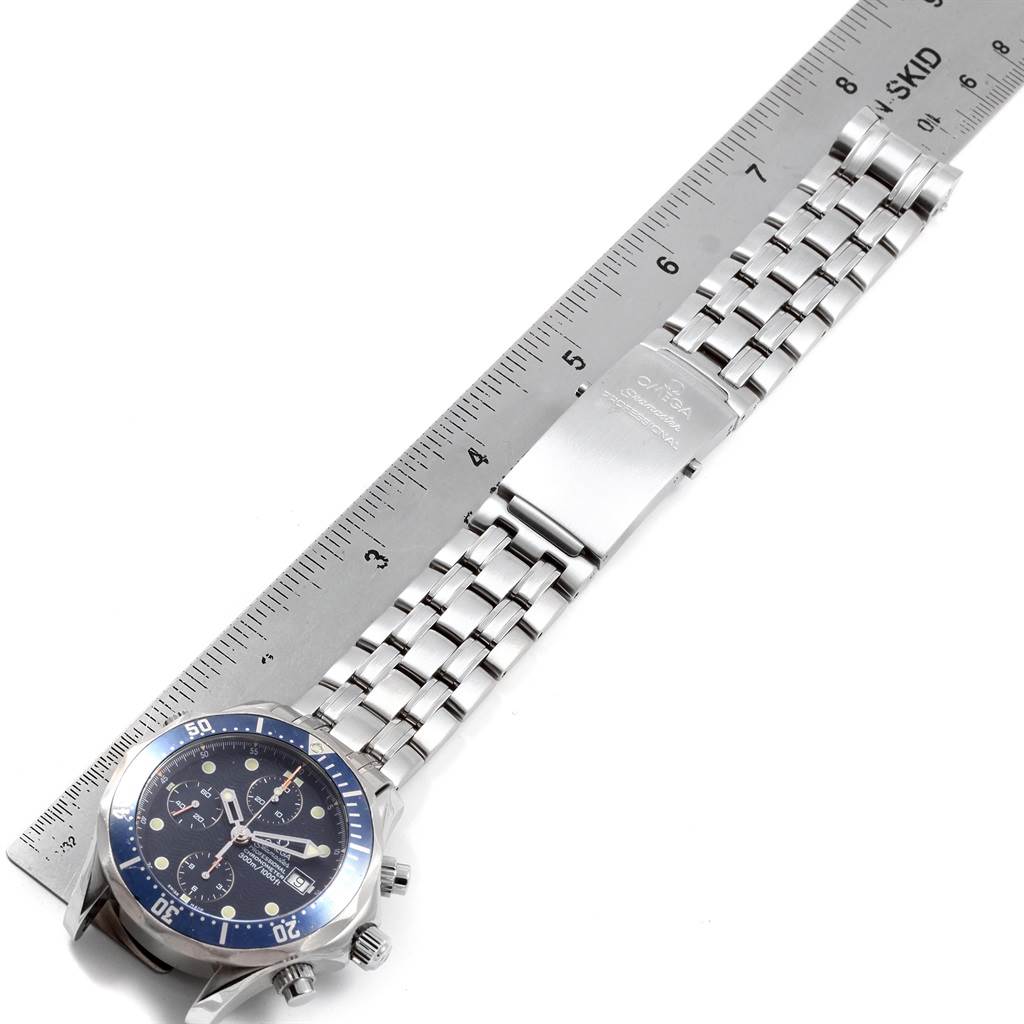 A horizontal view of an Omega Seamaster 2599.80.00 Men
s Stainless Steel Blue Dial 2599.80.00 Men
s Stainless Steel Blue Dial watch showing the face, bezel, crown, and metal bracelet on top of a ruler.