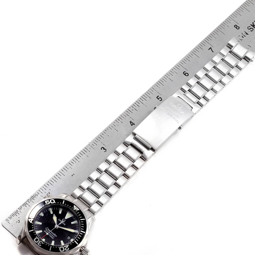 The image shows an Omega Seamaster 2262.50.00 Men
s Stainless Steel Black Dial 2262.50.00 Men
s Stainless Steel Black Dial watch laid flat with a metal ruler, displaying its dial and metal bracelet.