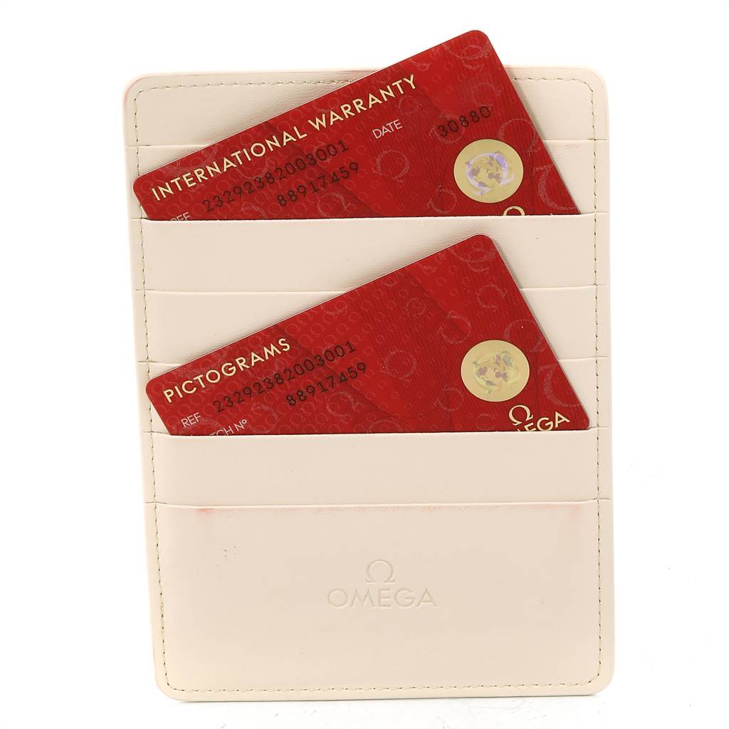 The image shows the International Warranty and Pictogram cards for an Omega Seamaster 232.92.38.20.03.001 Titanium Blue Dial 232.92.38.20.03.001 Titanium Blue Dial watch in a cream-colored cardholder.