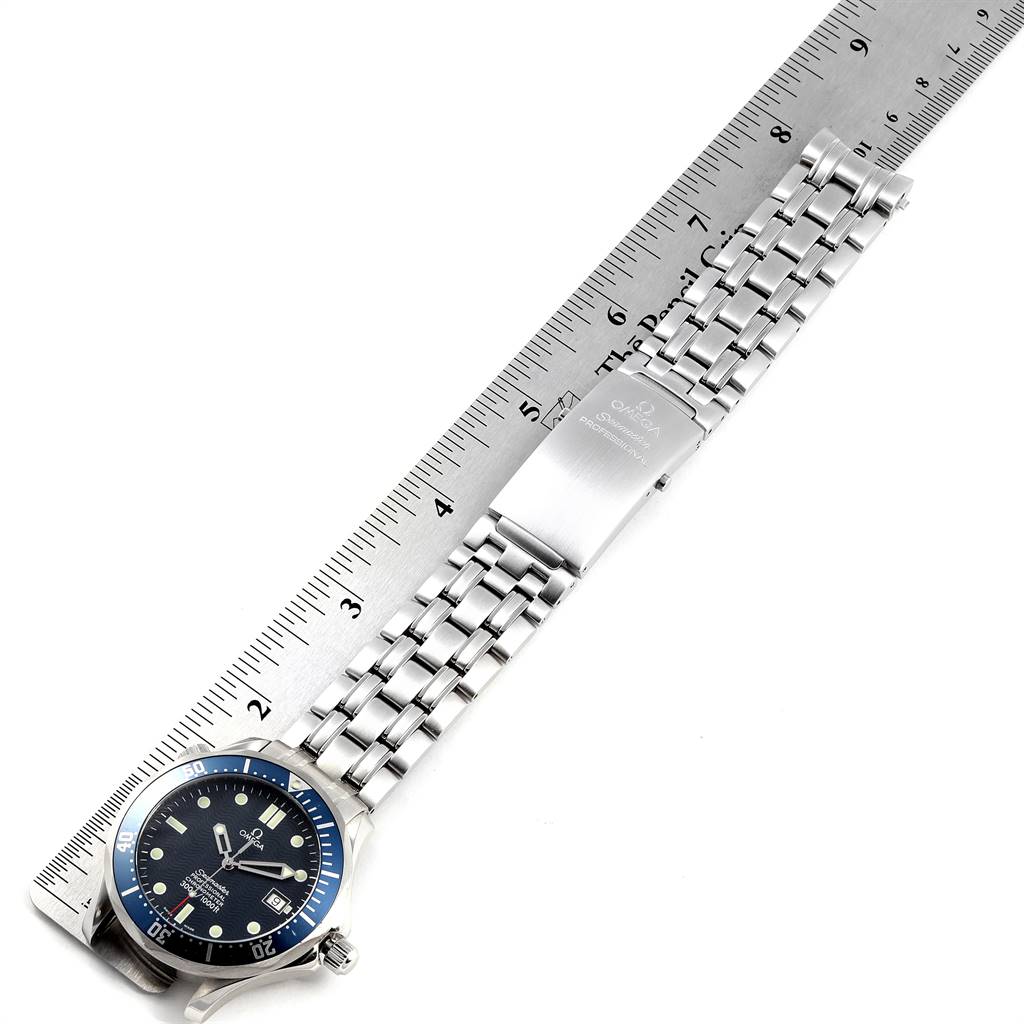 The Omega Seamaster 2531.80.00 Men
s Stainless Steel Blue Dial 2531.80.00 Men
s Stainless Steel Blue Dial watch is shown from a top-down angle, highlighting its face, bezel, bracelet, and clasp against a ruler for scale.