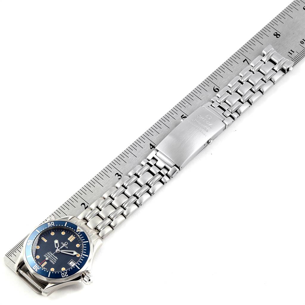 The image shows an Omega Seamaster 2551.80.00 Men
s Stainless Steel Blue Dial 2551.80.00 Men
s Stainless Steel Blue Dial watch laid out flat against a ruler, highlighting its bracelet and clasp.