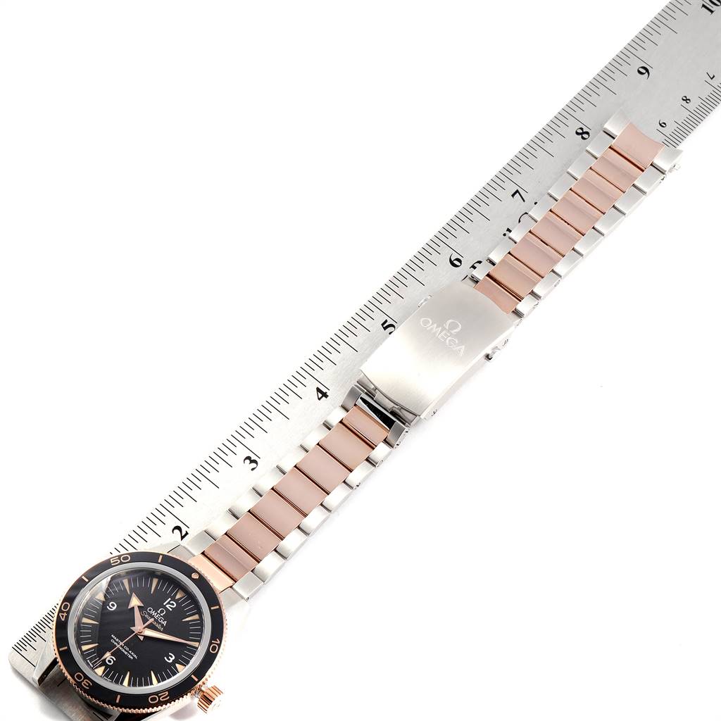 The image shows an Omega Seamaster 233.20.41.21.01.001 Men's Steel and Gold (two tone) Black Dial 233.20.41.21.01.001 Men's Steel and Gold (two tone) Black Dial watch with its band and clasp laid flat next to a ruler for scale.