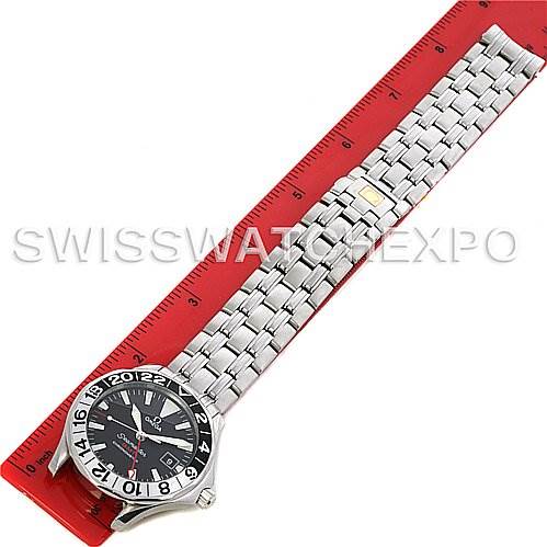 The Omega Seamaster 25345000 Men's Stainless Steel Black Dial 25345000 Men's Stainless Steel Black Dial watch is shown from an overhead angle, displaying its face and metal bracelet laid next to a red ruler.
