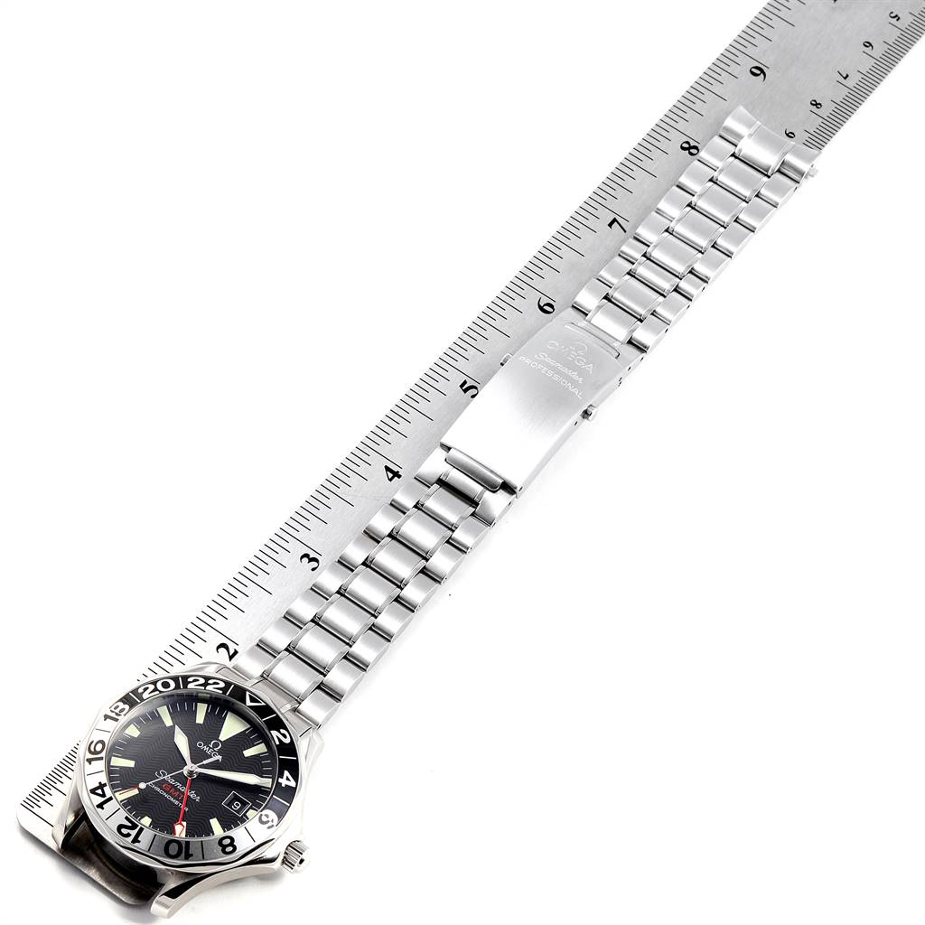 The image shows an Omega Seamaster 2234.50.00 Men
s Stainless Steel Black Dial 2234.50.00 Men
s Stainless Steel Black Dial watch laid flat next to a ruler, displaying its strap and face.