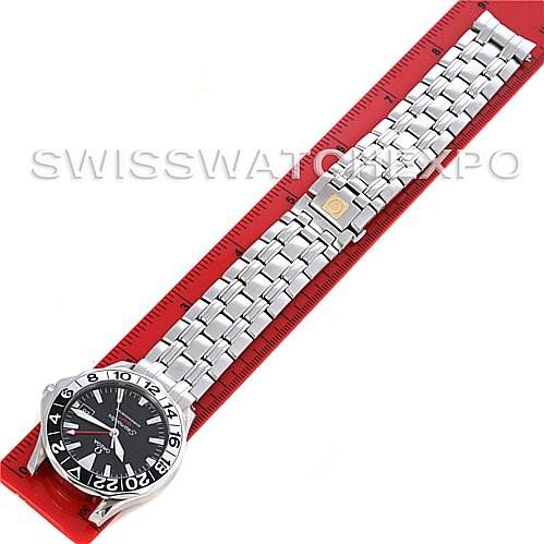 The Omega Seamaster 25345000 Men's Stainless Steel Black Dial 25345000 Men's Stainless Steel Black Dial watch is shown fully extended with its bracelet laid out on a red ruler.