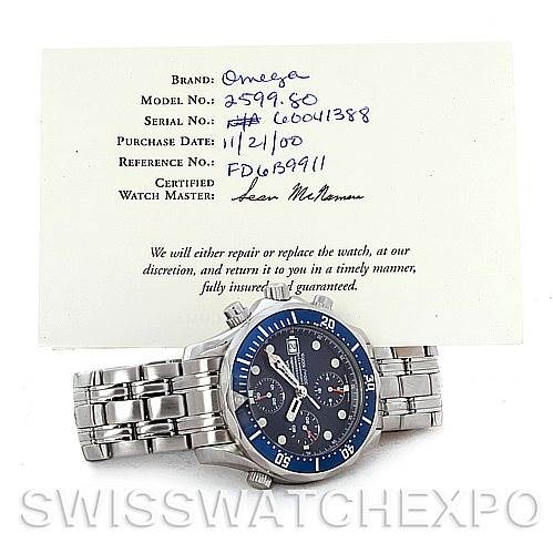 The image shows an Omega Seamaster 2599.80 Men's Stainless Steel Blue Dial 2599.80 Men's Stainless Steel Blue Dial watch laid flat with a warranty card document positioned above it.