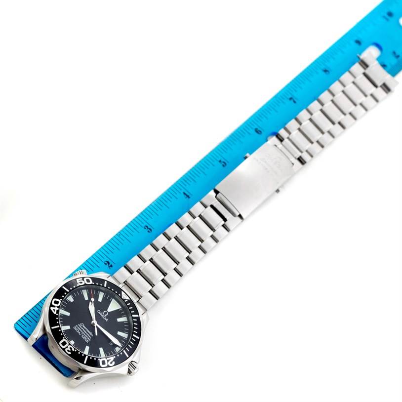 The Omega Seamaster 2254.50.00 Men
s Stainless Steel Black Dial 2254.50.00 Men
s Stainless Steel Black Dial watch is shown from a top-down angle, including the face and metal bracelet, alongside a blue ruler.