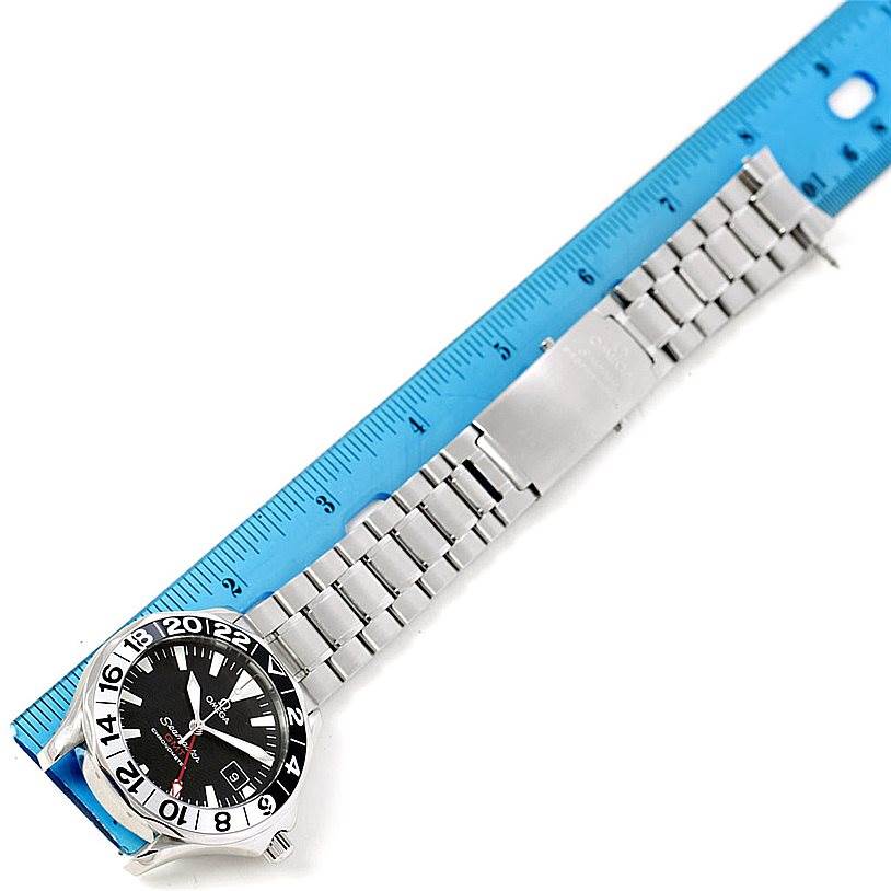 The image shows the Omega Seamaster 2234.50.00 Men
s Stainless Steel Black Dial 2234.50.00 Men
s Stainless Steel Black Dial watch lying flat with its stainless steel bracelet and clasp, alongside a ruler for scale.