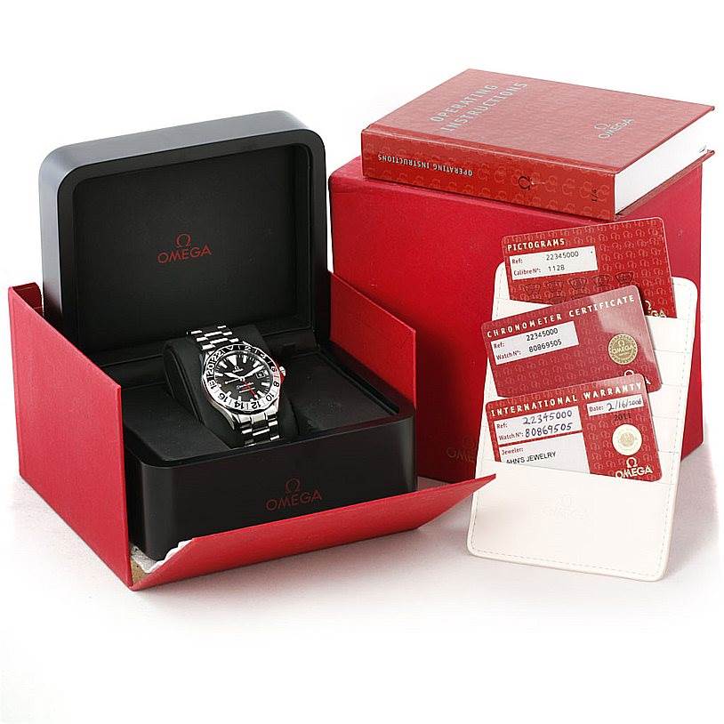 The Omega Seamaster 2234.50.00 Men
s Stainless Steel Black Dial 2234.50.00 Men
s Stainless Steel Black Dial watch is displayed at a front angle in its open box, accompanied by warranty cards and a user manual.