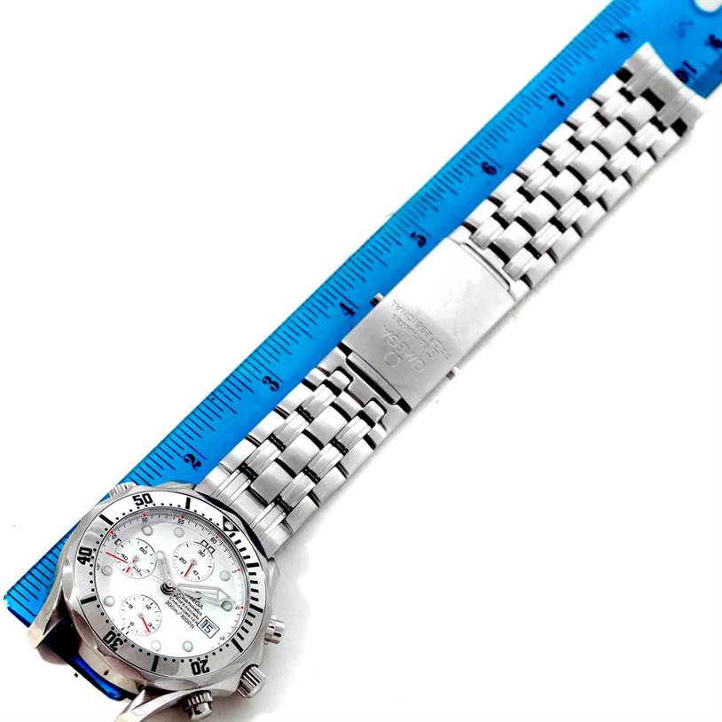 The Omega Seamaster 2598.20.00 Men
s Stainless Steel White Dial 2598.20.00 Men
s Stainless Steel White Dial watch is shown from an overhead angle, displaying its dial, bezel, and metal bracelet band alongside a ruler.