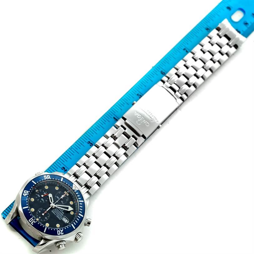 The image shows an Omega Seamaster 2599.80.00 Men
s Stainless Steel Blue Dial 2599.80.00 Men
s Stainless Steel Blue Dial watch laying flat with its face and metal bracelet alongside a blue measuring ruler.