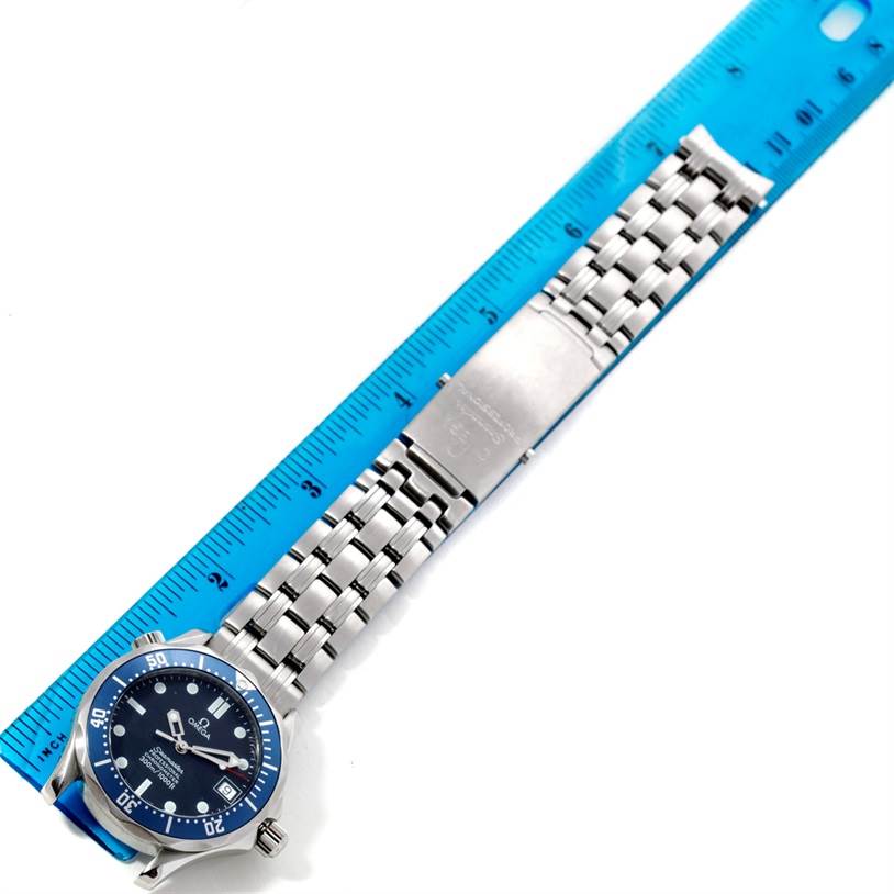 The image shows an Omega Seamaster 2551.80.00 Men
s Stainless Steel Blue Dial 2551.80.00 Men
s Stainless Steel Blue Dial watch and its metal bracelet laid flat next to a blue ruler for size reference.