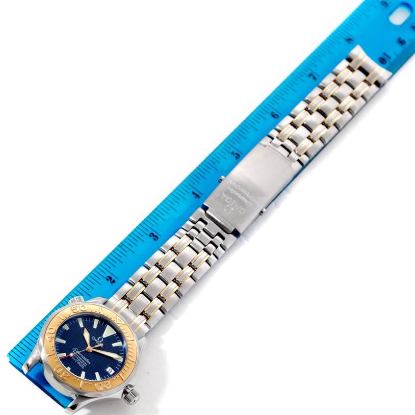 The image shows an Omega Seamaster Men
s Stainless Steel Blue Dial Men
s Stainless Steel Blue Dial watch laid flat with its face and full bracelet visible, alongside a blue measuring ruler.