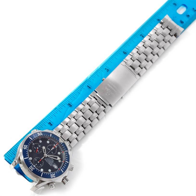 The image shows an Omega Seamaster 2599.80.00 Men
s Stainless Steel Blue Dial 2599.80.00 Men
s Stainless Steel Blue Dial watch laid flat next to a blue measuring ruler, displaying its blue dial and metal bracelet.