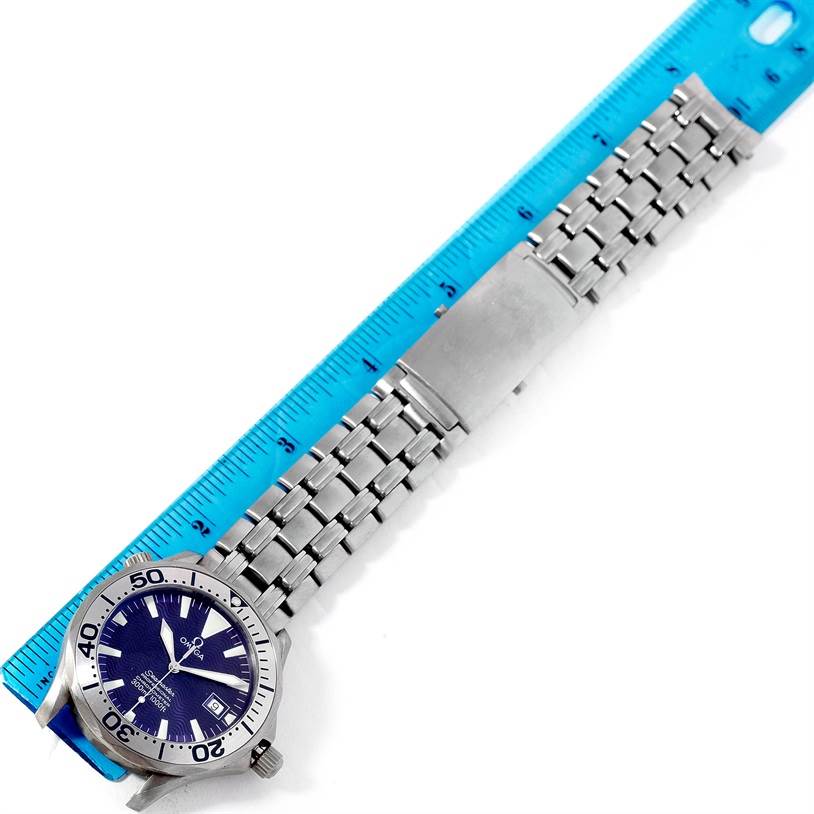 The Omega Seamaster 2231.80.00 Men's Titanium Blue Dial 2231.80.00 Men's Titanium Blue Dial watch is shown from a top-down angle, featuring its face, bezel, and metal bracelet positioned next to a ruler.