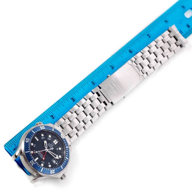 The image shows an Omega Seamaster 2535.80.00 Men's Stainless Steel Blue Dial 2535.80.00 Men's Stainless Steel Blue Dial watch from a top-down angle, featuring its face, bezel, and metal bracelet placed next to a blue ruler.