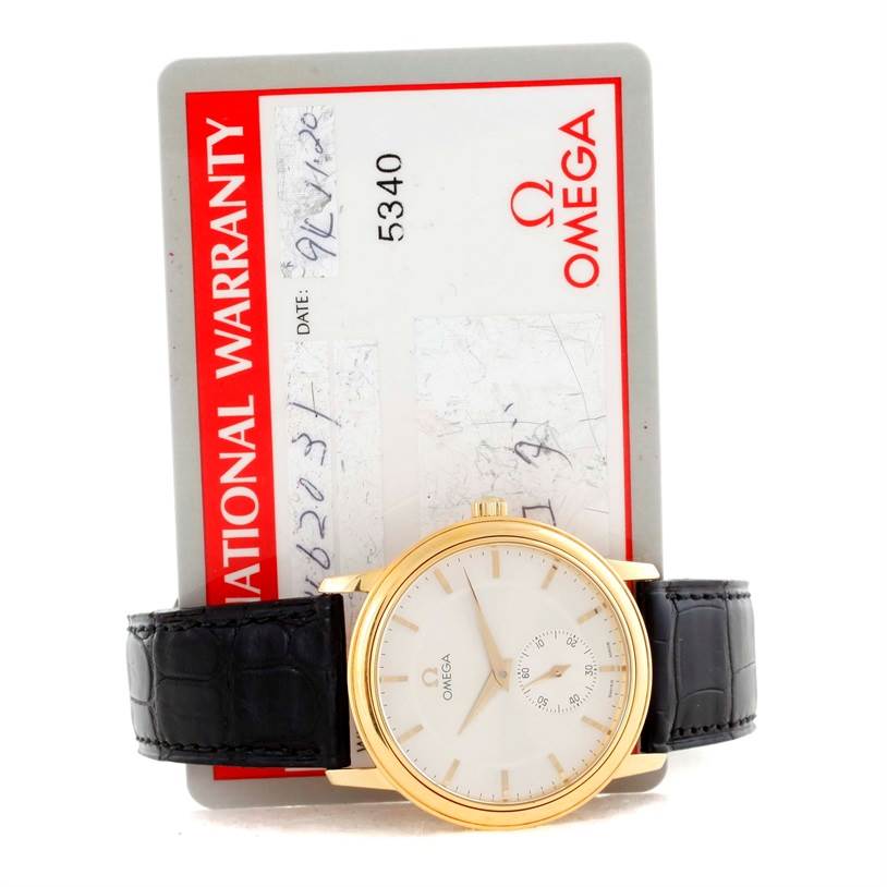 The image shows the front of an Omega De Ville 4620.31 Men's Yellow Gold Silver Dial 4620.31 Men's Yellow Gold Silver Dial watch with its warranty card behind it.