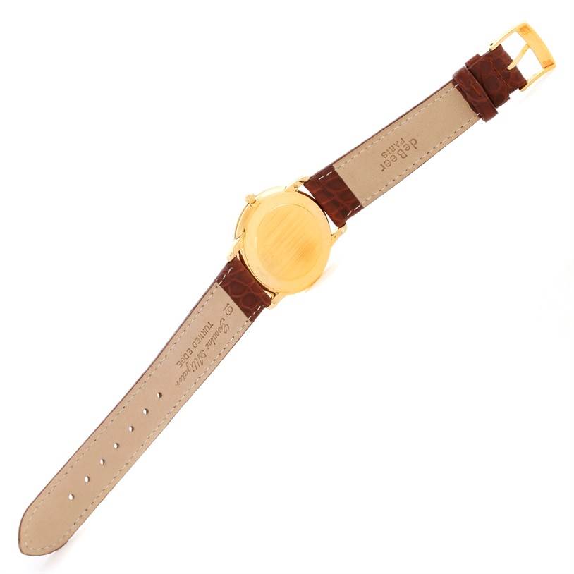 The image shows the back of an Omega De Ville Men's Yellow Gold Silver Dial Men's Yellow Gold Silver Dial watch, featuring a brown leather strap and a gold-tone case.
