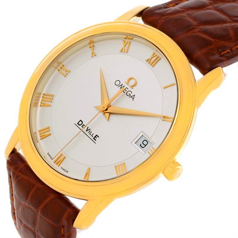 This image shows the Omega De Ville Men's Yellow Gold Silver Dial Men's Yellow Gold Silver Dial watch from an angle that highlights the face, gold casing, and brown leather strap.