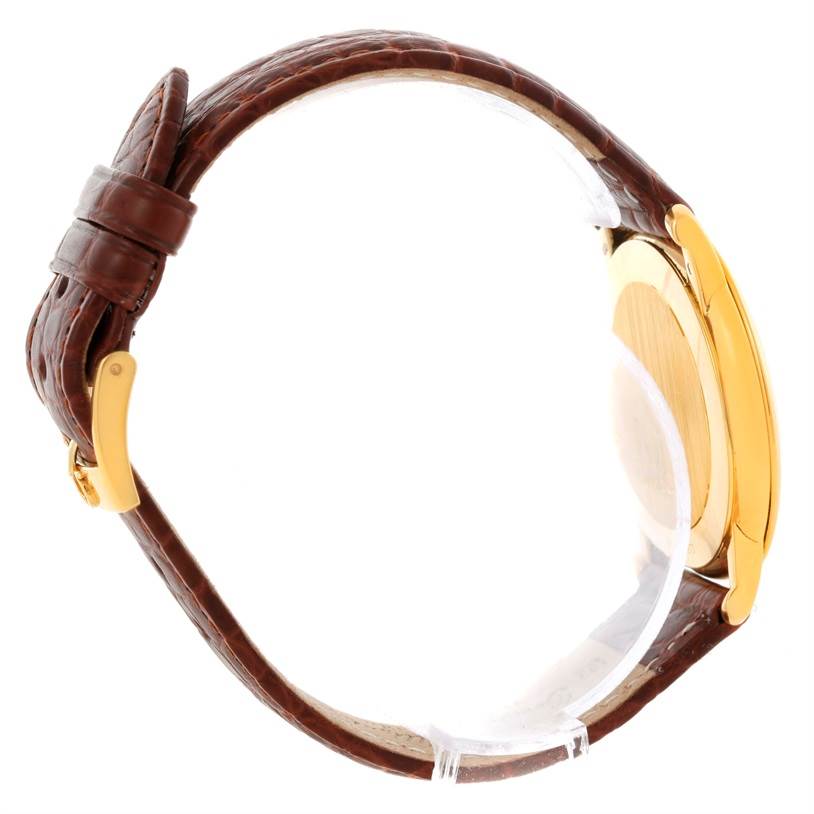 The image shows a side view of the Omega De Ville Men's Yellow Gold Silver Dial Men's Yellow Gold Silver Dial watch, highlighting its brown leather strap and gold-tone case.